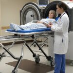 Una paciente acostada en una cámara de oxígeno hiperbárico y el médico atendiéndola_