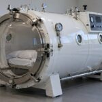 white hard-shell hyperbaric chamber with pressure gauges and control panel