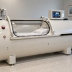 white hard-shell 2 atmosphere hyperbaric chamber with pressure gauge and control panel